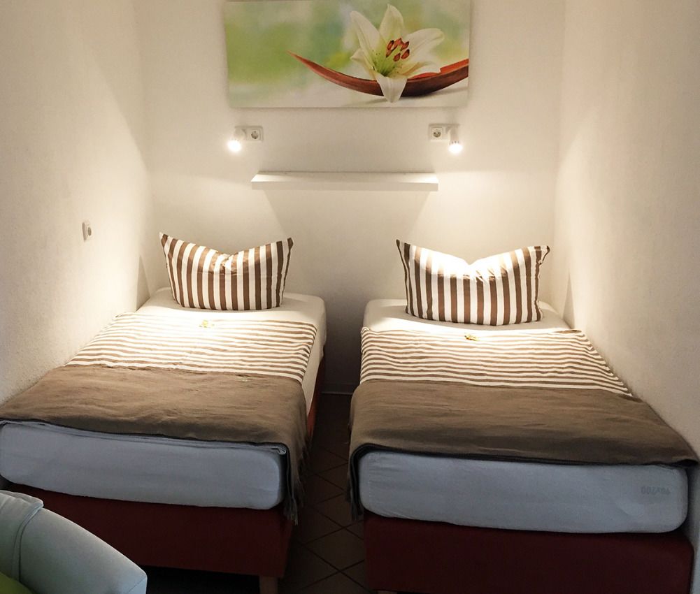 A room with two beds, each with striped pillows and a brown blanket.
