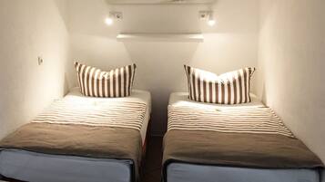 A room with two beds, each with striped pillows and a brown blanket.