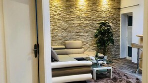 A modern living room with a stone wall, a sofa, a coffee table, and a plant.