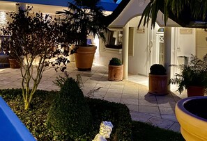 Une cour intérieure agrémentée de plantes en pot, d’une statue et de l’entrée d’un bâtiment.