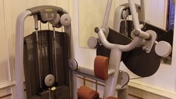Un gimnasio con una bicicleta estática, una máquina de press de banca y un espejo en la pared.