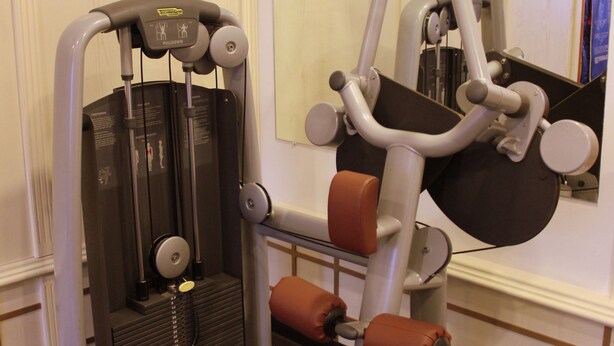 A gym with a stationary bike, a chest press machine, and a mirror on the wall. - Helena Sands (Nessebar)