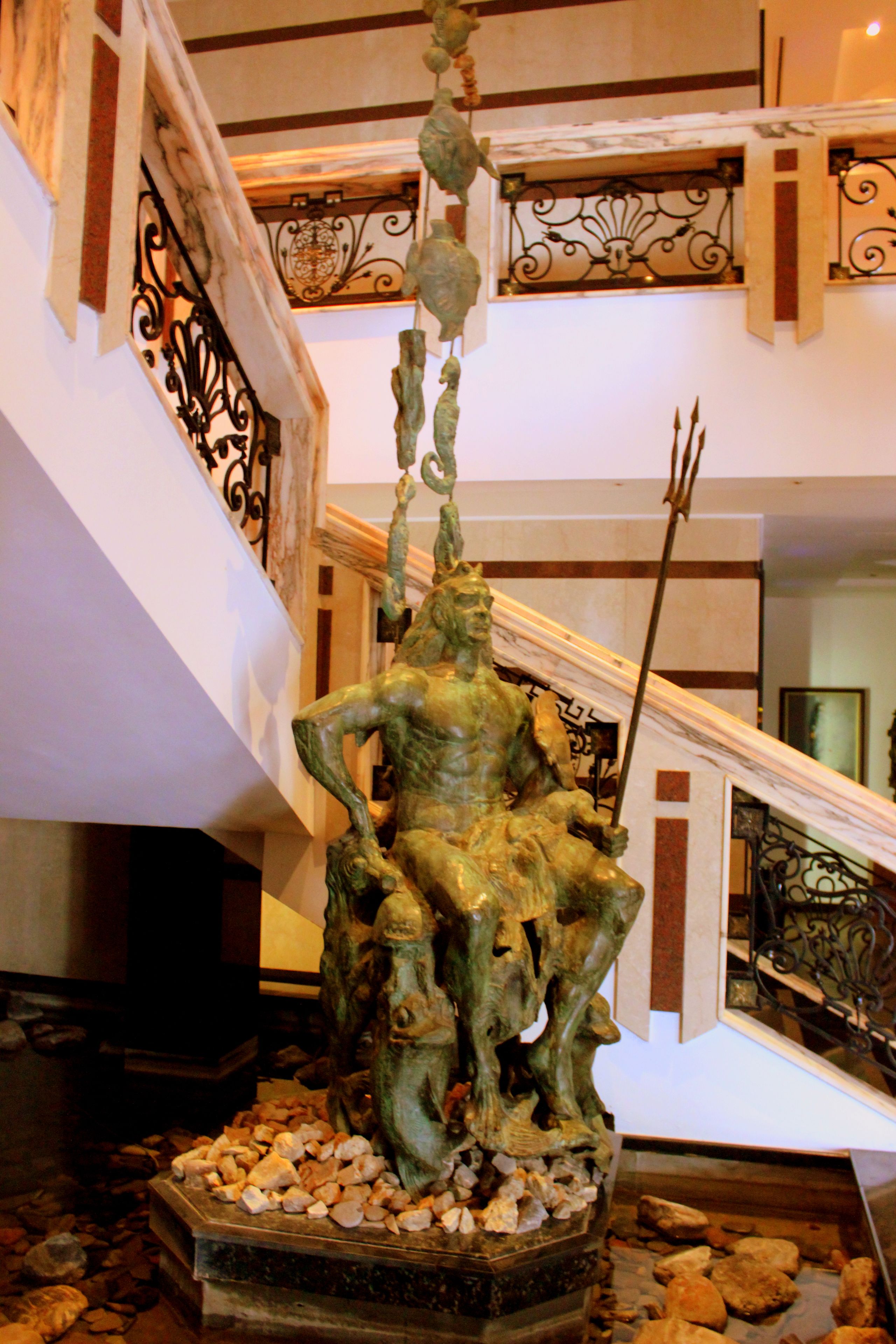 Una estatua en un vestíbulo con una escalera y barandillas decorativas.