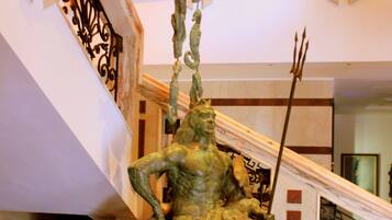 Una estatua en un vestíbulo con una escalera y barandillas decorativas.