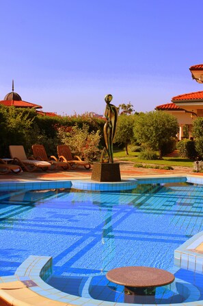 Una piscina con sillas de descanso y una escultura.