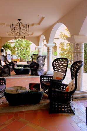 An outdoor seating area with wicker furniture, a glass-top table, and a chandelier. - Helena Sands (Nessebar)