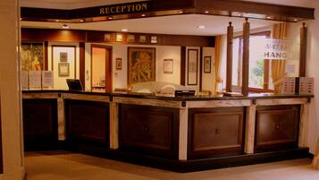 A reception area with a marble counter, framed artwork, and a sign indicating the reception desk.