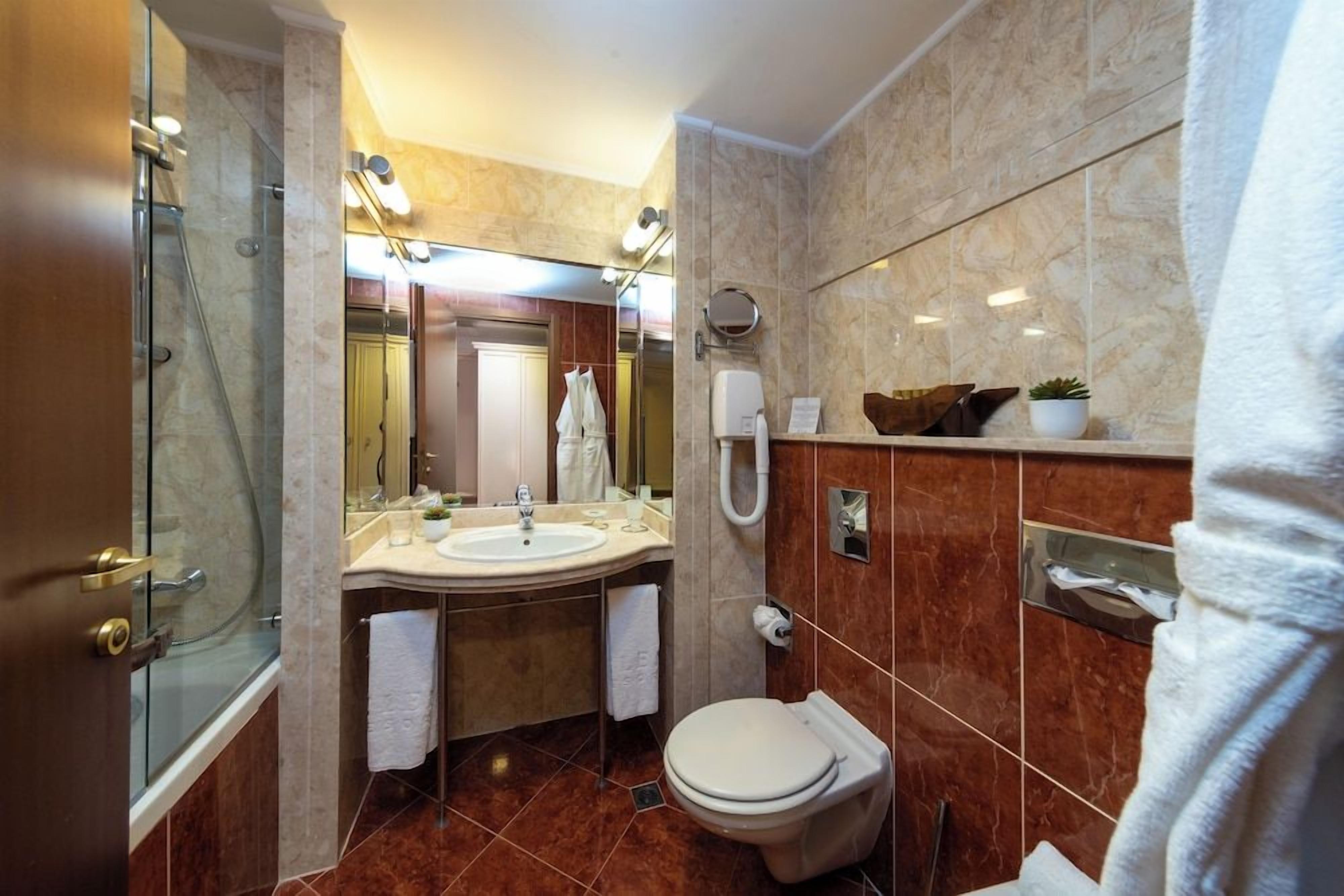 A modern bathroom with a glass shower enclosure, a sink, a toilet, and a vanity with a mirror.