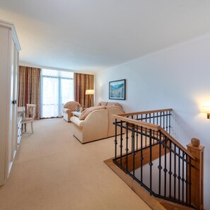 A spacious living area with a staircase, a sofa, a chair, and a lamp. - Helena Sands (Nessebar)