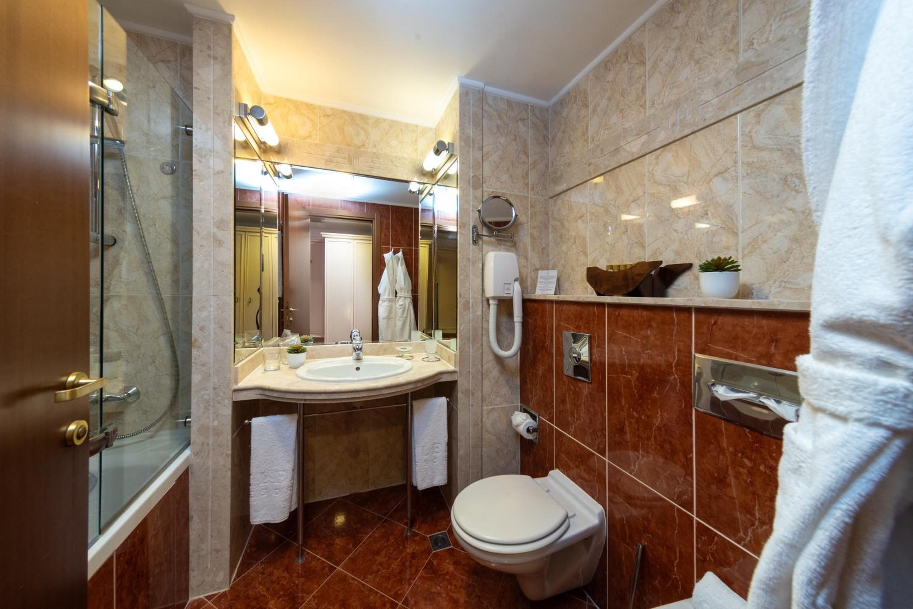 A modern bathroom with a glass-enclosed shower, a sink with a mirror, a toilet, and a towel rack.
