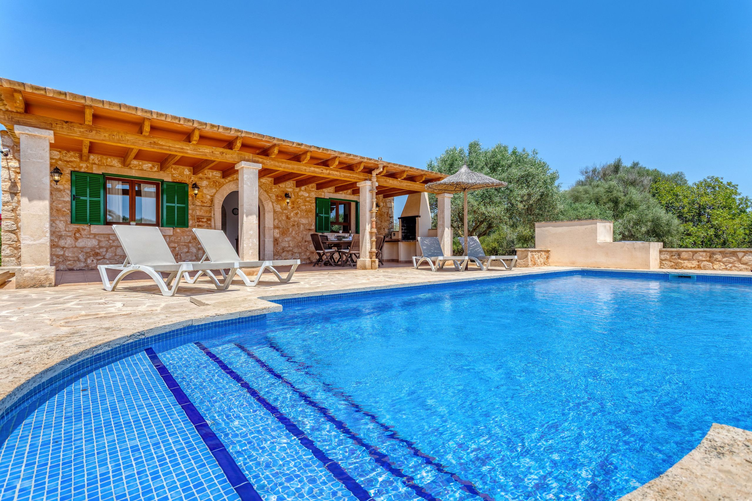A swimming pool with lounge chairs and a pergola.