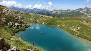 Un paisaje montañoso con un lago cristalino, terreno rocoso y montañas distantes.