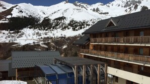 Un edificio de estilo chalet con fachada de madera y un balcón, con montañas nevadas al fondo.
