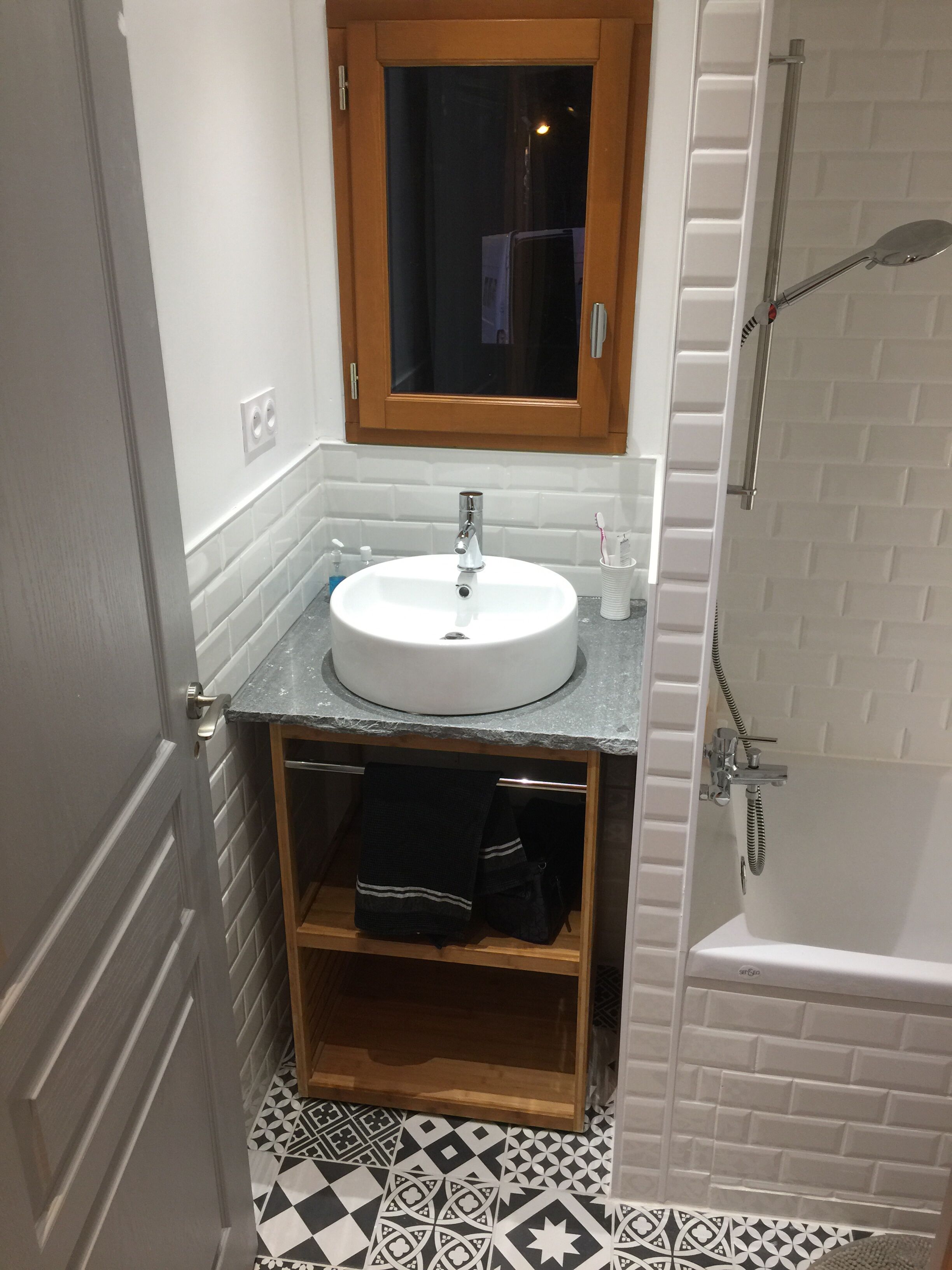 A bathroom with a white sink, wooden cabinet, and a shower area.