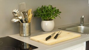 A kitchen counter with a cutting board, knives, a plant, and a utensil holder.