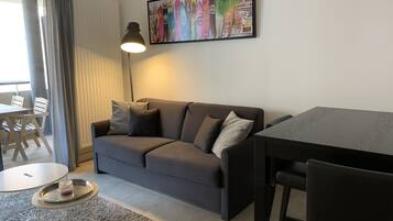 Una sala de estar moderna con un sofá gris, una mesa de comedor y una lámpara de pie.
