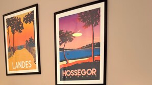 A hotel room with a bed, pillows, a nightstand, a lamp, and two framed pictures on the wall.