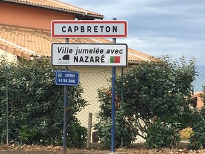 Una señal de calle indica Capbreton, una señal para la Avenida Notre Dame, y una señal que muestra que Capbreton es un pueblo encantador con Nazaré.