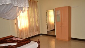Un dormitorio con cama, armario, espejo y ventana con cortinas.