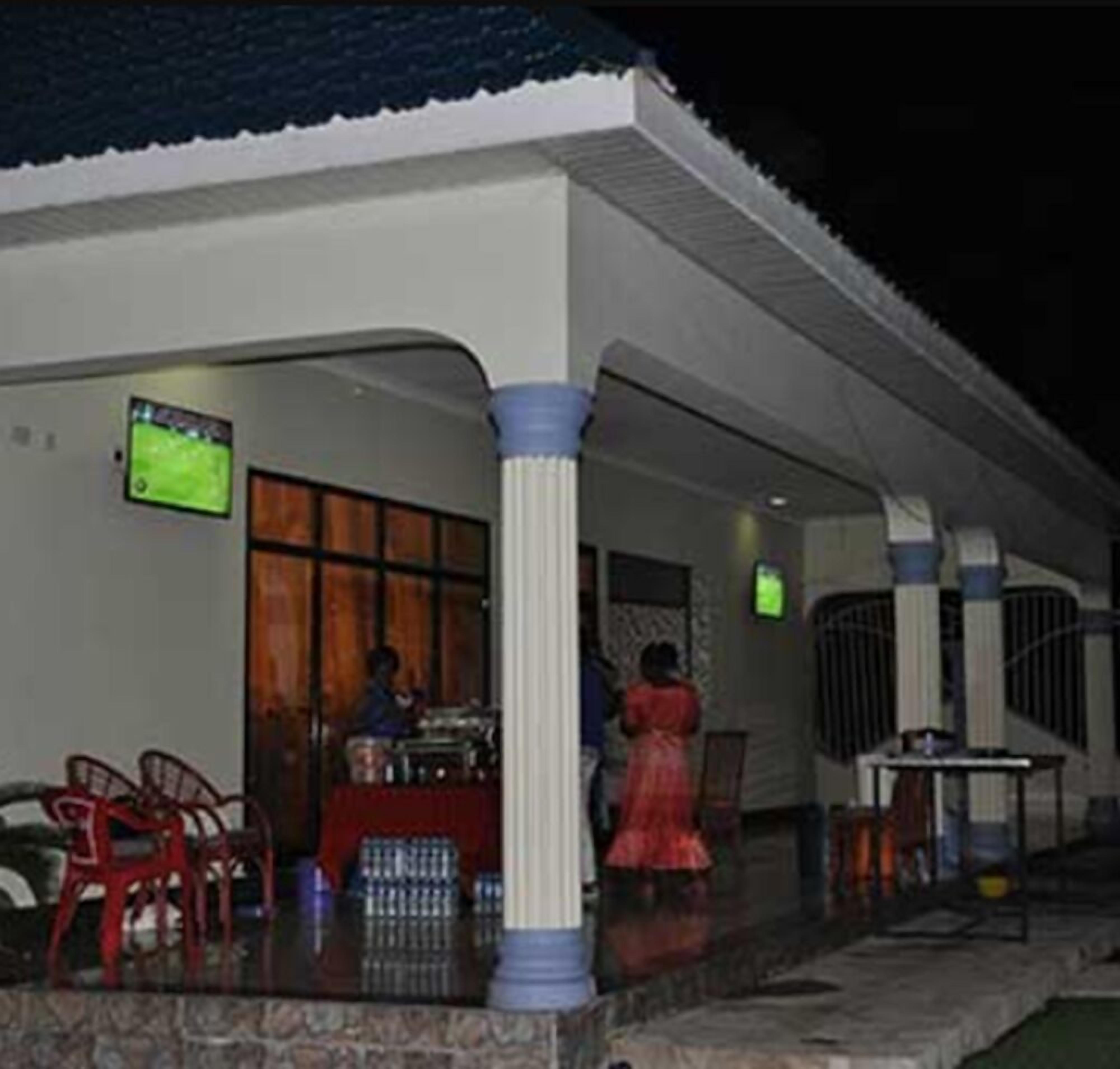 A covered outdoor area with a bar, red chairs, and a person in a red dress.