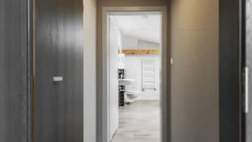 A hallway leading to a bathroom with a wooden ceiling and white tiles.