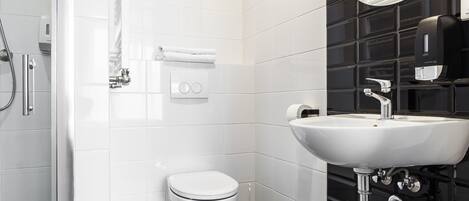 A modern bathroom with a white toilet, a sink, and a shower.