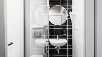 Un baño moderno con dos lavamanos, un espejo redondo y un secador de pelo.