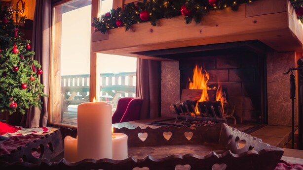 A cozy room with a fireplace, a Christmas tree, and heart-shaped candle holders.