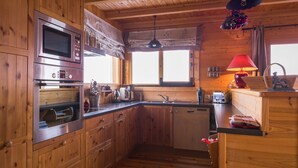 A wooden cabin kitchen with a Bosch oven, a sink, a window, and a red lamp.