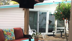 Un patio con un sofá de mimbre, una mesa con mantel azul y una planta en maceta.
