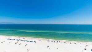 Une plage bordée de rangées de parasols bleus et de chaises longues.