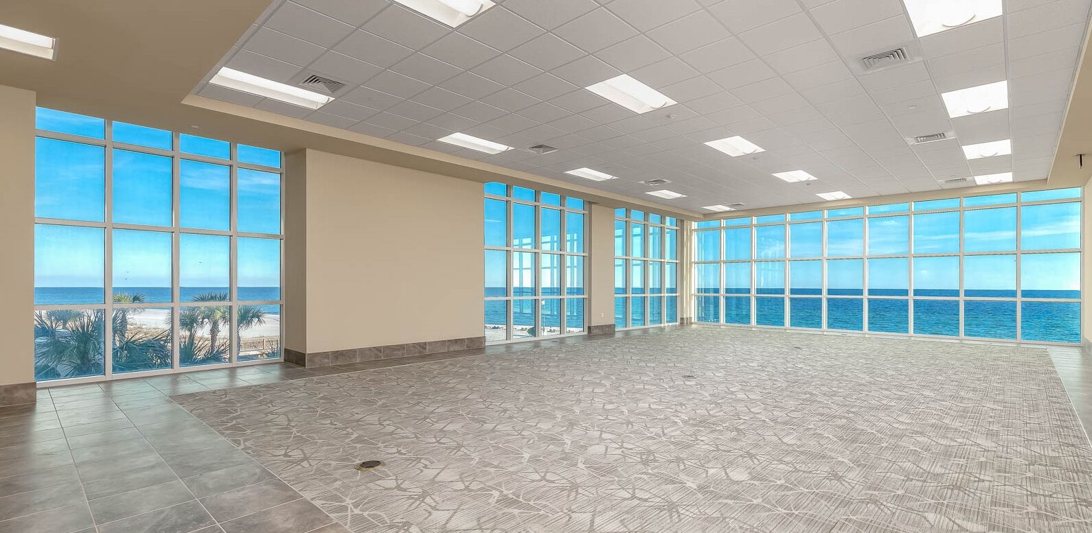 A spacious room with large windows offering a view of the ocean.