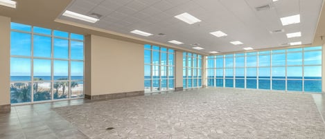 A spacious room with large windows offering a view of the ocean.