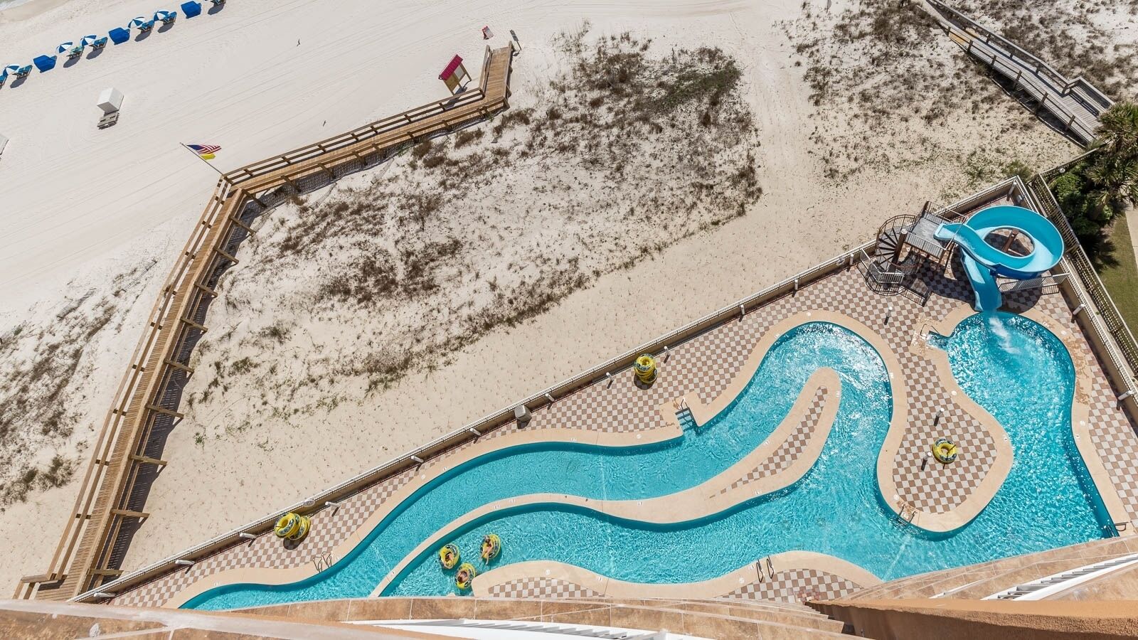 A pool with a wave design, a wooden deck, and a lifeguard stand.