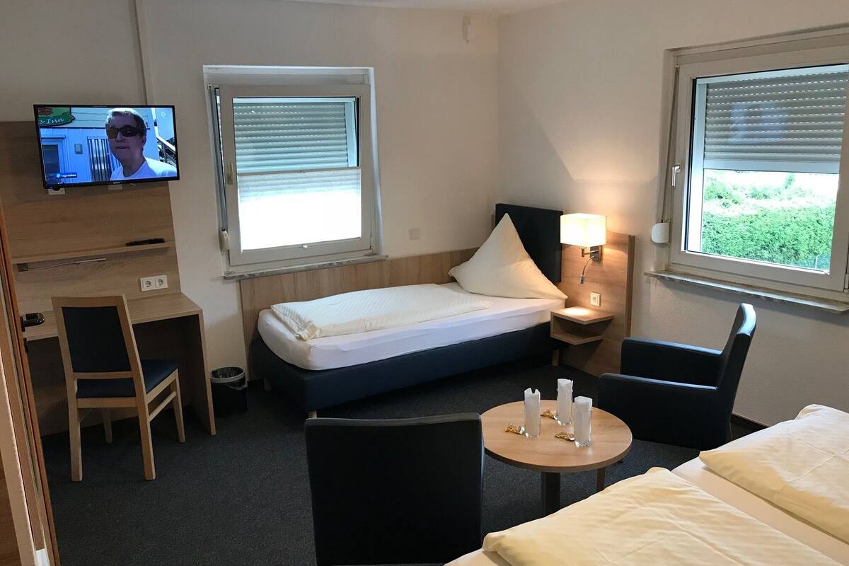 Une chambre d’hôtel avec un lit, un bureau, une chaise, une télévision et une fenêtre.