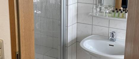 A bathroom with a shower, sink, and mirror.