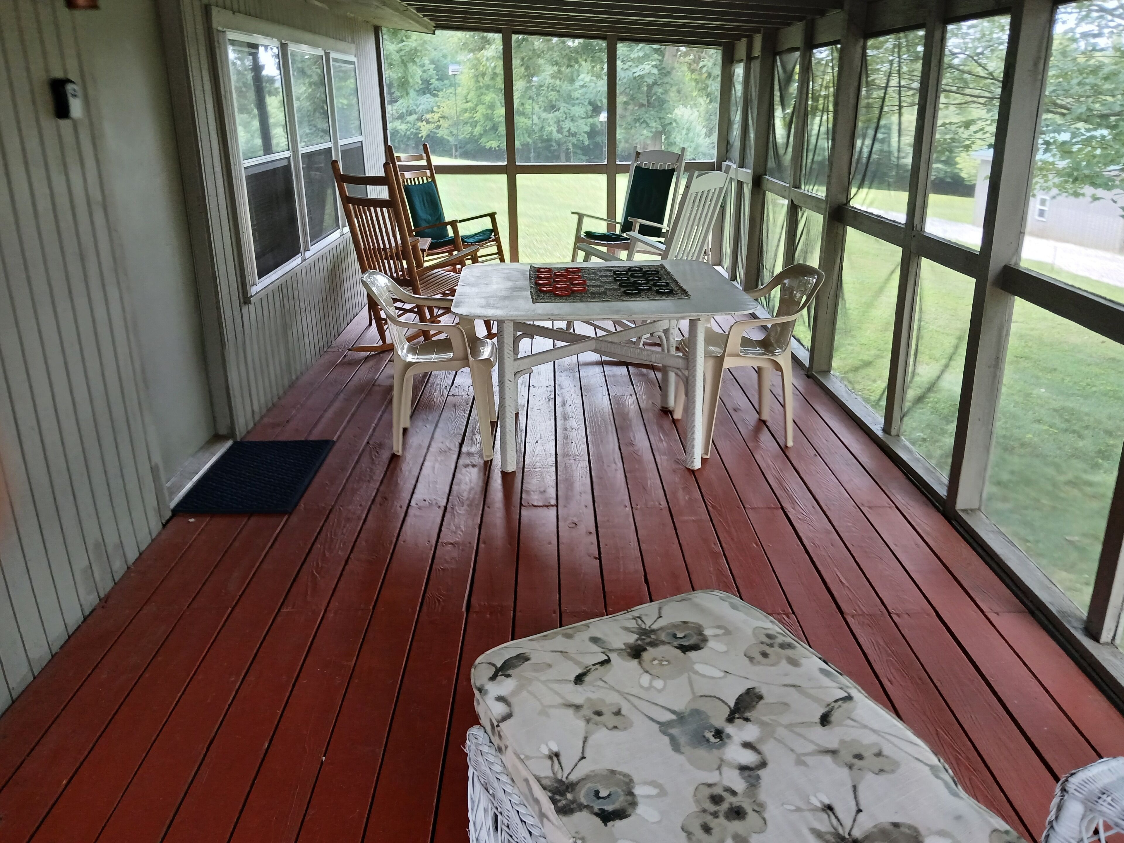 En overdækket terrasse med træterrasse, et bord med stole og en blomstret sofa.