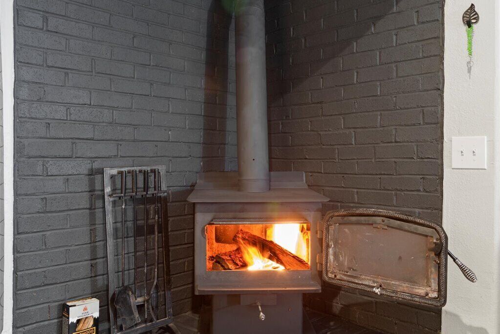 A wood-burning stove with a visible fire, a metal grate, and a chimney.