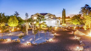 Una casa spaziosa a due piani con un vialetto illuminato e un giardino.