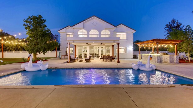 Un'ampia casa con piscina, area salotto esterna e luci decorative.
