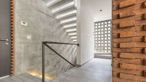 A modern interior with a concrete wall, a metal handrail, and a brick wall with a geometric pattern. - Steps from the Beach Luxury Suite w/Private Pool (San Francisco)