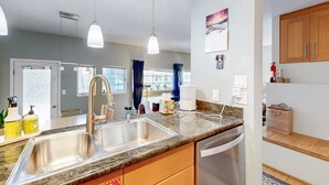 A modern kitchen with granite countertops, stainless steel appliances, and pendant lighting.