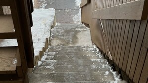 A staircase leading up to a wooden door, with snow on the steps and ground.