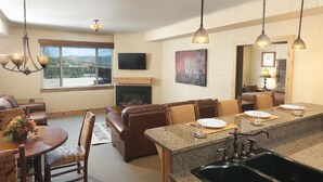A modern kitchen with granite countertops, a black sink, and a dining area with a round table and chairs. - Equipped Suite | Sauna + Spa Access (Park City)