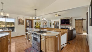 A spacious kitchen with wooden cabinets, a central island, and a large window offering a view of the outdoors. - Adventures-Historic Deadwood- Trails- ATV- Skiing-Trolly-Private Acreage (Deadwood)