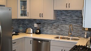 A modern kitchen with white cabinets, a stainless steel refrigerator, a dishwasher, a stove, and a sink with a faucet. - Huntington Beach Townhome style apartment, close to pier, beach and Pacific City (Huntington Beach)