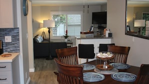 A dining area with a wooden table, four chairs, and a central decorative piece. - Huntington Beach Townhome style apartment, close to pier, beach and Pacific City (Huntington Beach)