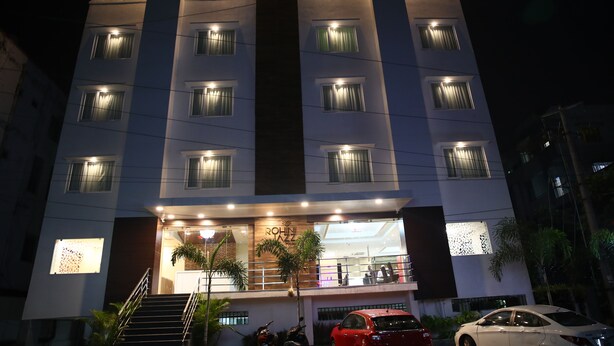 Un hôtel à plusieurs étages, doté de fenêtres illuminées et d’une entrée bien visible.