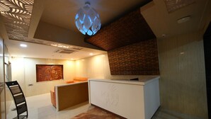 Un espace d’accueil au design moderne, comprenant un comptoir d’accueil, une grande peinture abstraite et un plafond à motifs.