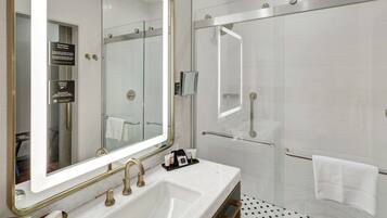 Un baño moderno con un espejo grande, lavamanos dobles y cabina de ducha con vidrio.